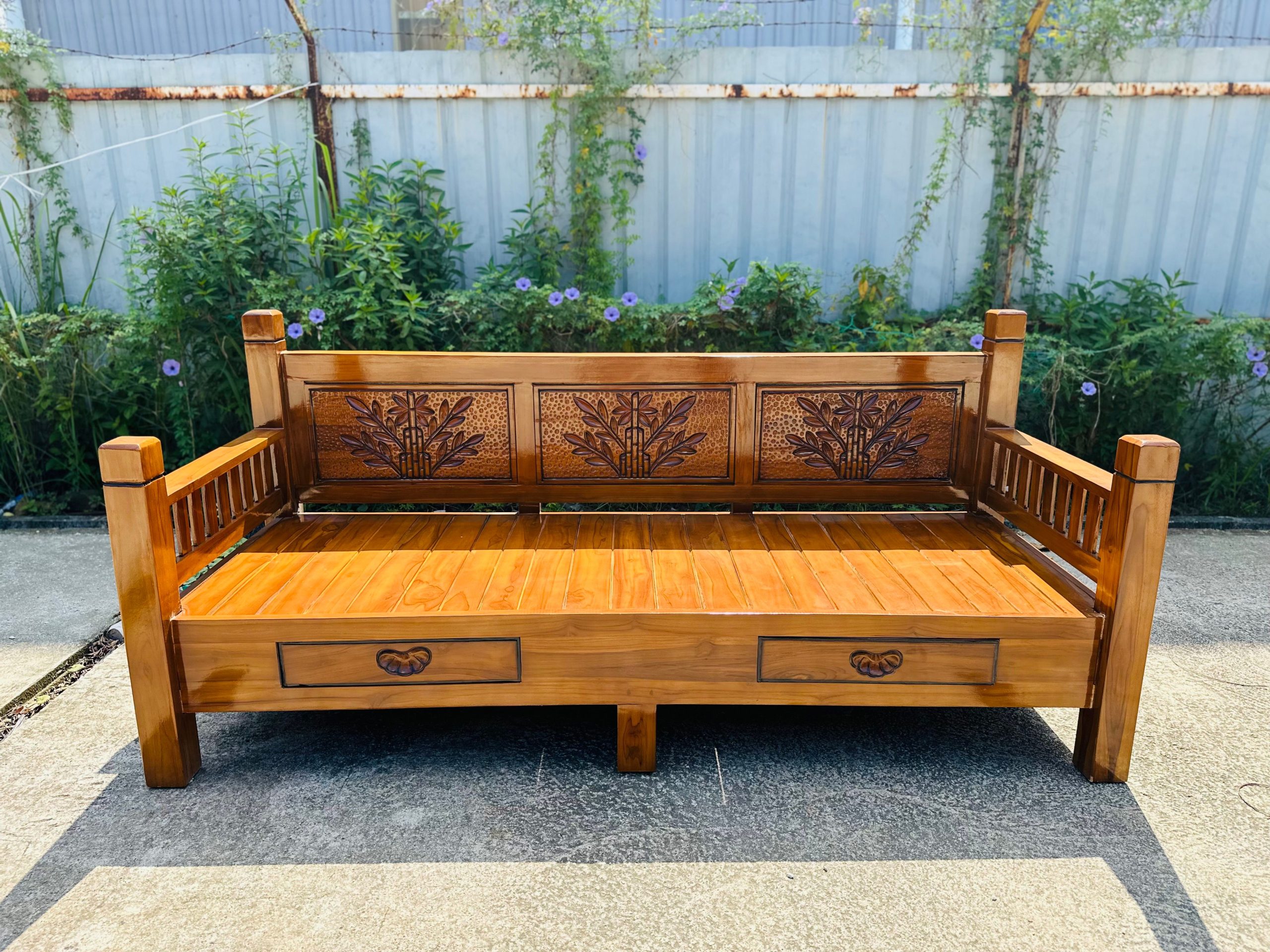Banc en teck sculpté fleuri dans un jardin