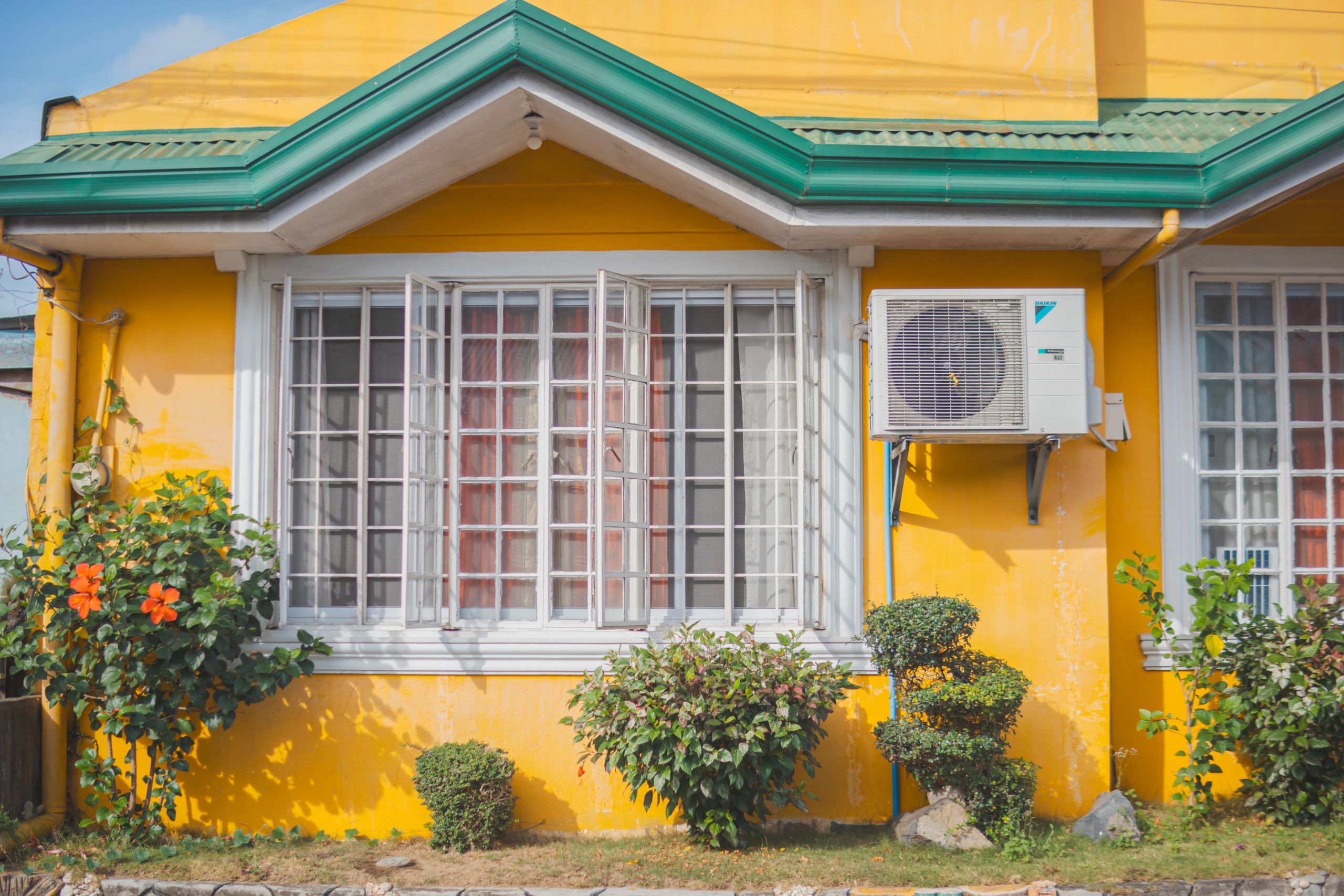 Maison jaune toit vert plantes climatisation