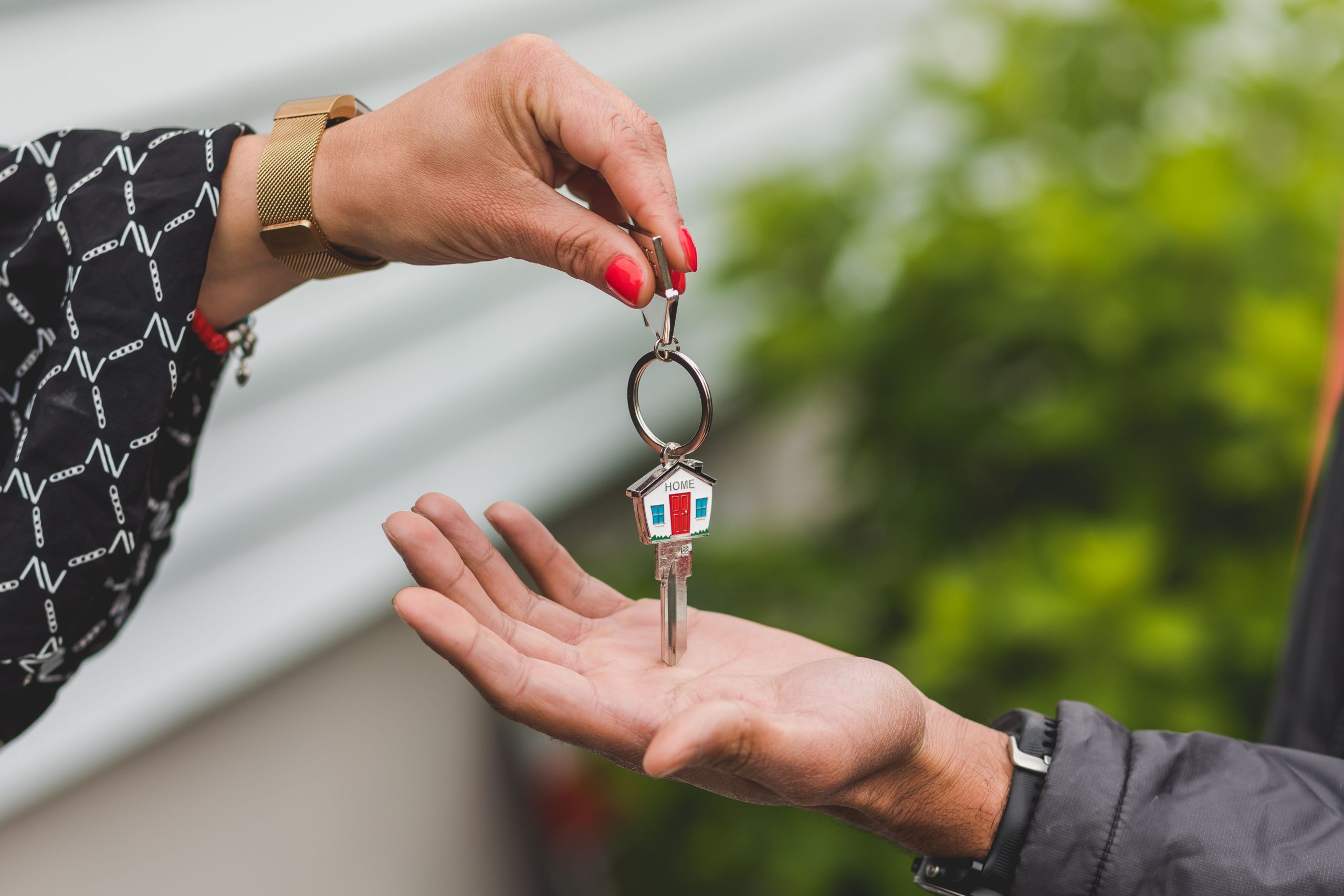 Main remettant une clé avec porte-clés maison