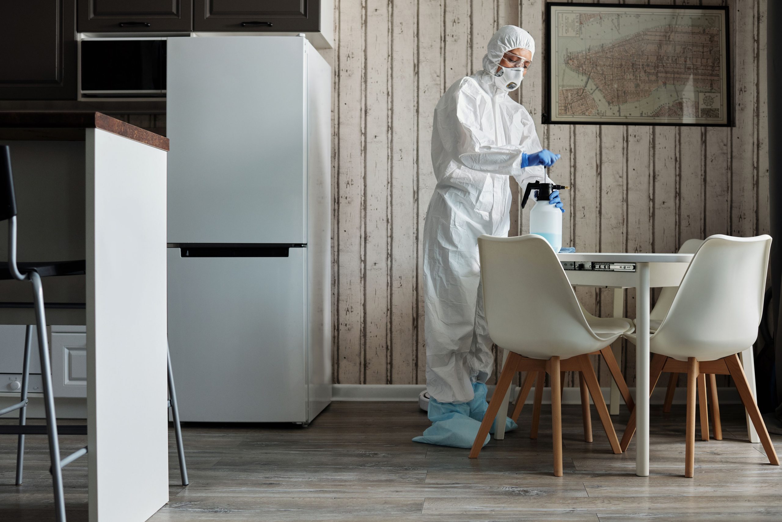 Personne en combinaison désinfecte table cuisine