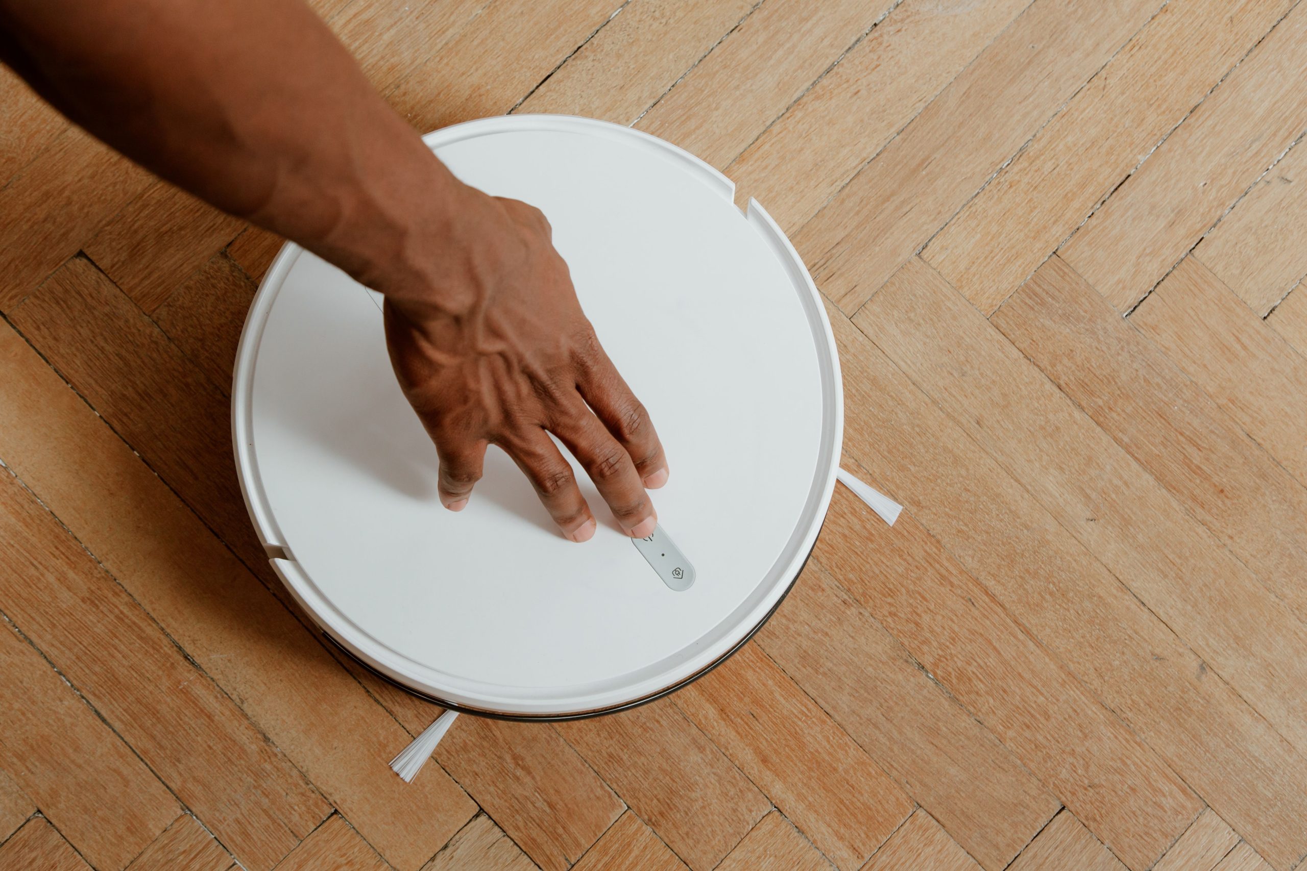 Main activant aspirateur robot laveur sur parquet bois