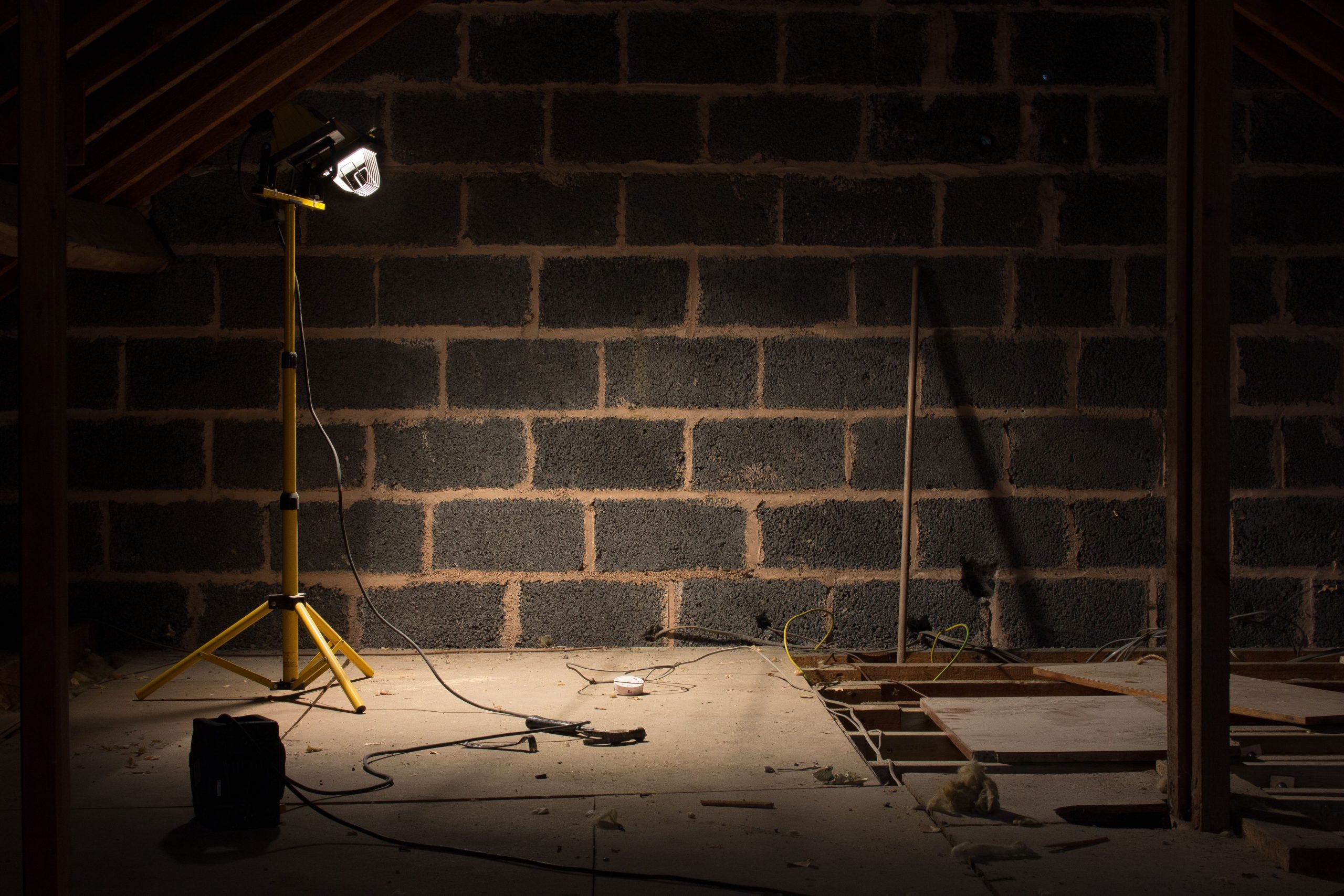 Grenier sombre en rénovation avec lampe de chantier