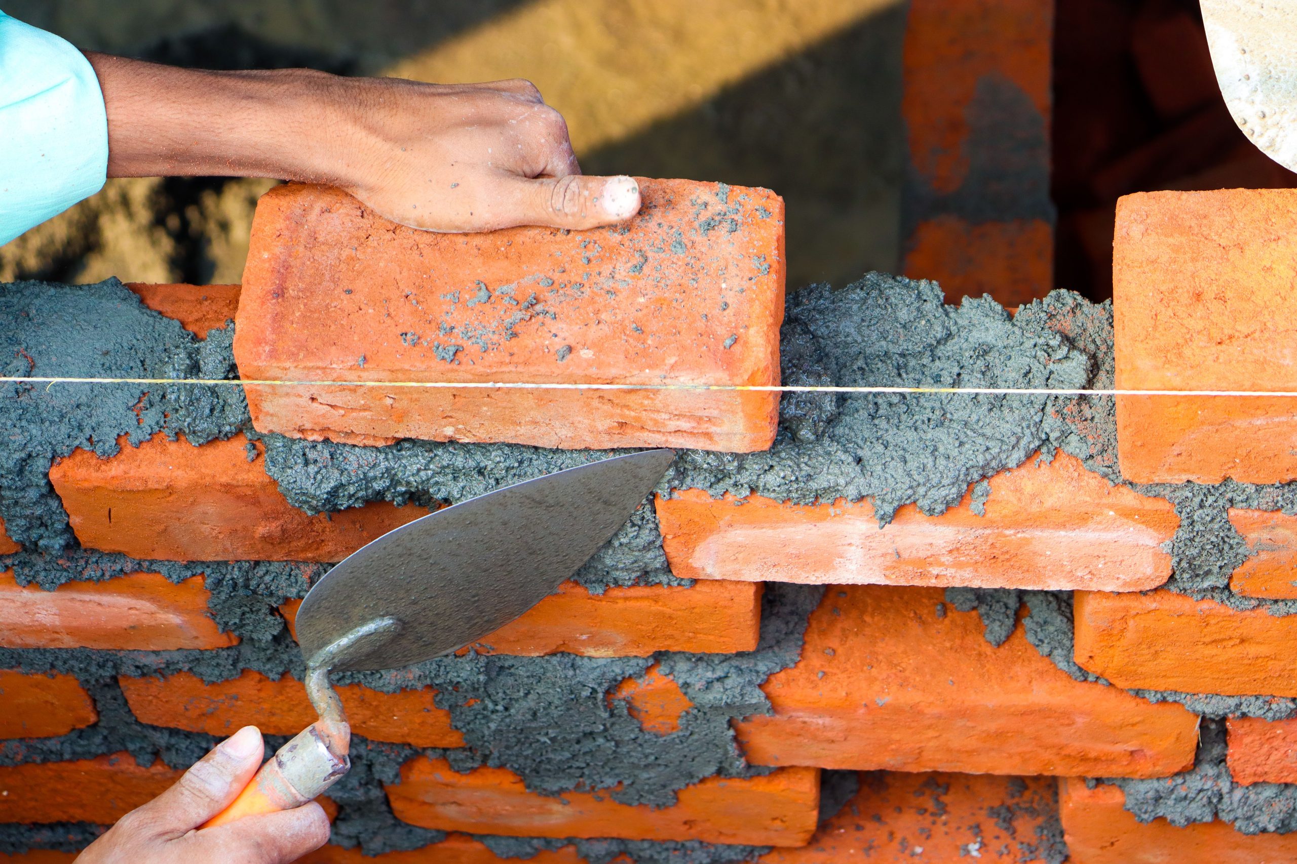 Pose de briques au ciment en maçonnerie professionnelle