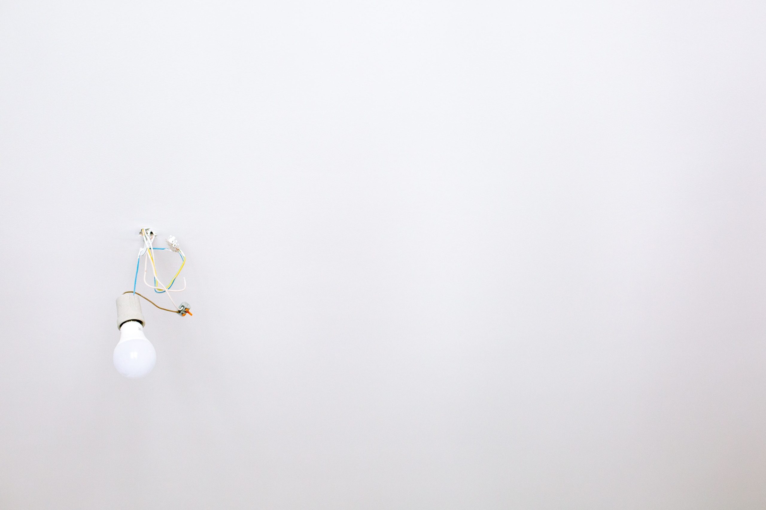 Ampoule minimaliste suspendue au plafond blanc.